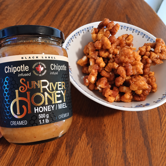 Sun River Honey Chipotle Creamed Honey beside a bowl of honey caramel popcorn twists.